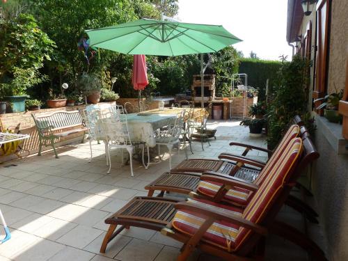 a patio with chairs and a table with a green umbrella at Gîte Les Iris in Crecy la Chapelle