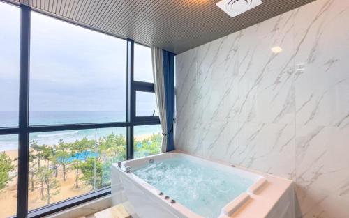 Una bañera en un baño con una ventana grande. en 안목을높이다 펜션, en Kyŏnso