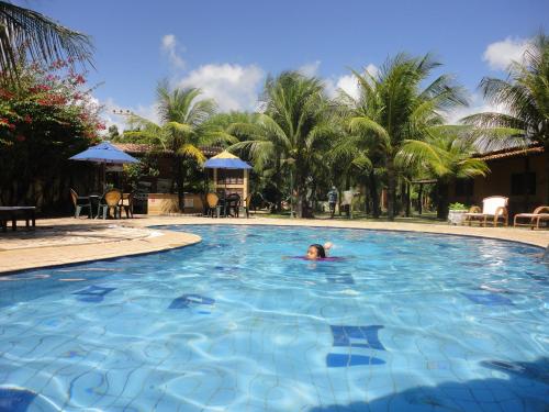 a woman swimming in a swimming pool at a resort at Hotel Enseada Maracajaú in Maracajaú