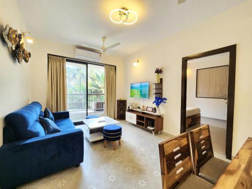 a living room with a blue couch and a large mirror at Beachside 1BHK Apartment - Pool, Gym & Modern Comforts, Candolim in Candolim