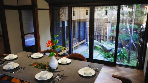 a dining room table with a view of a garden at Basara Kinmokusei 金木犀Kyoto Machiya in Kyoto