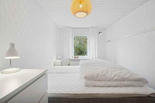 Dormitorio blanco con cama y lámpara en Beautifull 2-Room Apartment With Sea View, en Sandvig