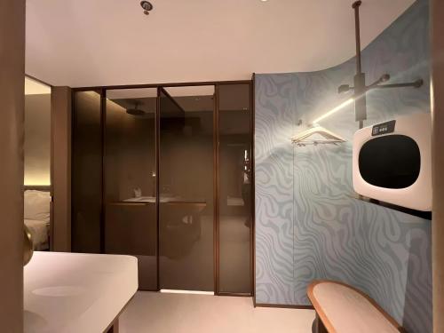 Una habitación con un televisor en una pared al lado de un dormitorio. en Elong Hotel Qingdao Golden Beach, en Qingdao