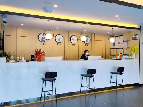 a woman wearing a face mask stands behind a counter in a restaurant at GreenTree Inn Express Jinan Zhangqiu Districty Ancinet Town Longquan Road in Zhangqiu