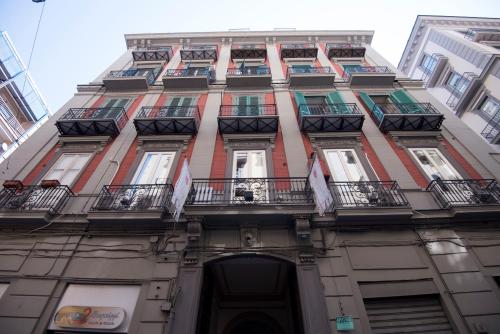 un edificio alto con balcones y banderas. en Schilizzi Hotel, en Nápoles