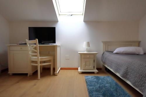 a bedroom with a bed and a desk with a television at Kolpinghaus in Caransebeş