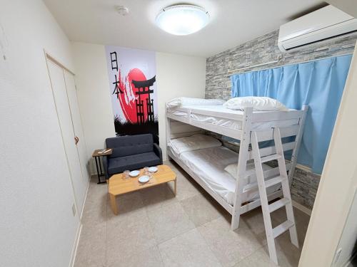 ein Zimmer mit zwei Etagenbetten und einem Tisch in der Unterkunft ハイツ緑ヶ丘103 in Nagasaki