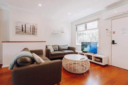a living room with a couch and a tv at Beach Holiday Apartments in Rye