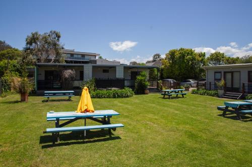 a picnic table with an umbrella on the grass at Beach Holiday Apartments in Rye