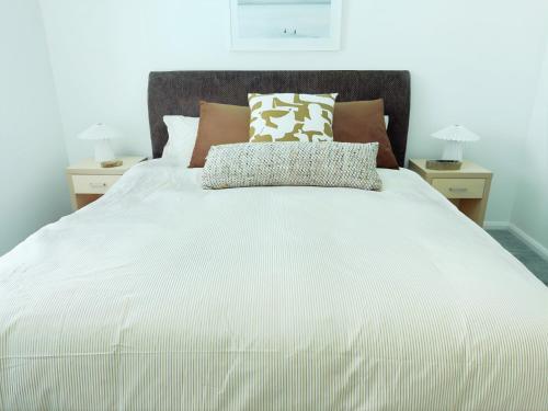 een groot wit bed met 2 nachtkastjes en 2 lampen bij Oaks Port Stephens Pacific Blue Resort - Sea Salt Studio in Salamander Bay