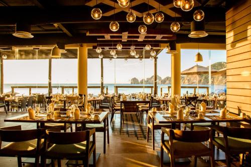 een restaurant met tafels en stoelen en uitzicht op de oceaan bij Casa Dorada Los Cabos Resort & Spa in Cabo San Lucas