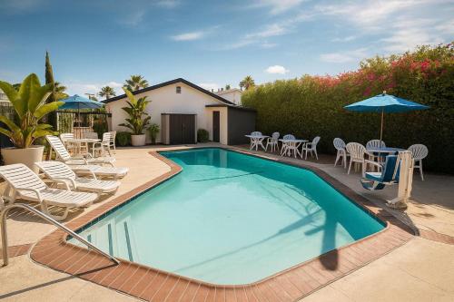 a swimming pool with chairs and tables and umbrellas at Travelodge by Wyndham LAX in El Segundo