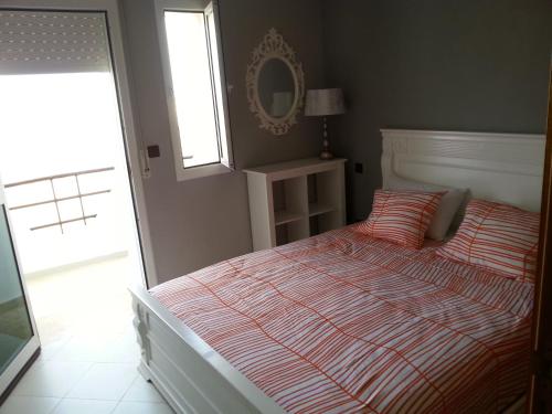 a bedroom with a bed and a window and a mirror at Apartment dans Residence avec piscine à Achakar in Jebila