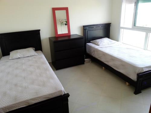 a bedroom with two beds and a mirror on the wall at Apartment dans Residence avec piscine à Achakar in Jebila