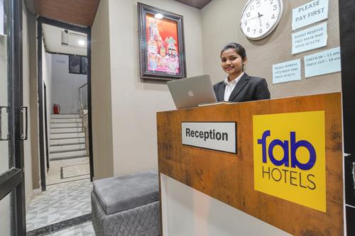 a woman standing at a reception desk with a laptop at Fabhotel Grand Blue in Indore
