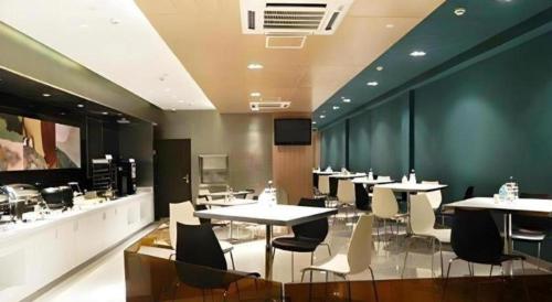 a dining room with tables and chairs and avertisement at Jinjiang Inn Zhangjiagang Yangshe West Street Pedestrian Street in Zhangjiagang