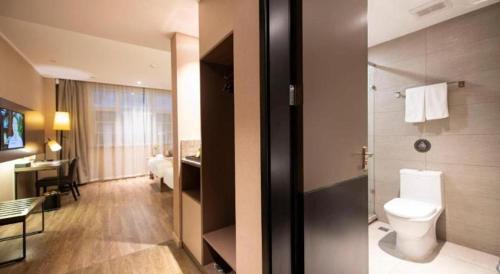 a bathroom with a toilet and a room with a desk at Yitel Tai'an Taishan Hongmen Daimiao in Tai'an