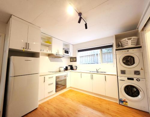 a kitchen with white cabinets and a washer and dryer at Aloha Bayside Private guest room sleeps 5 with free parking in Highett