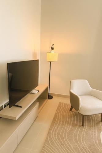 a living room with a tv and a chair at Elegant 1BR Yas Island with Theme Park Views & Exclusive Yas Park Offers in Abu Dhabi