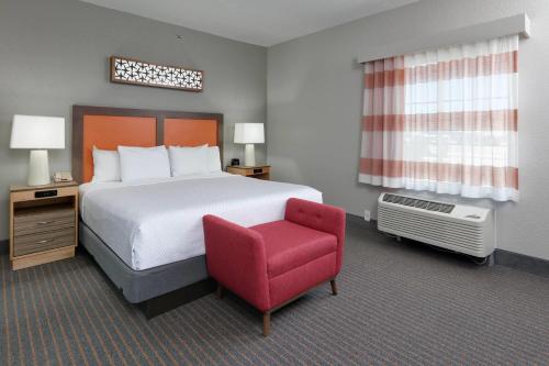 a hotel room with a bed and a red chair at La Quinta by Wyndham Dallas Love Field in Dallas