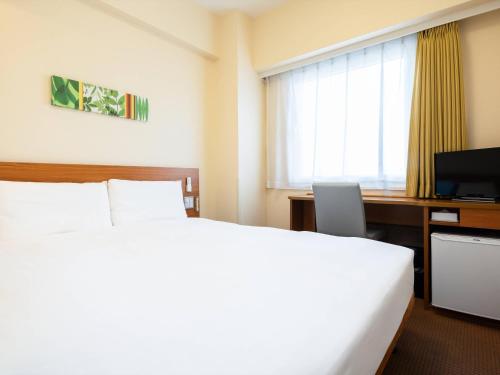 a hotel room with a bed and a desk and a television at Comfort Inn Kurashiki Mizushima in Kurashiki