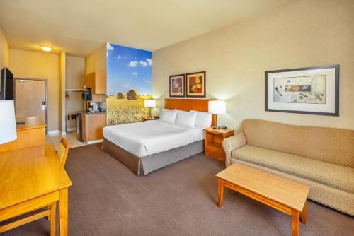 a hotel room with a bed and a couch at Clarion Pointe in Rimbey