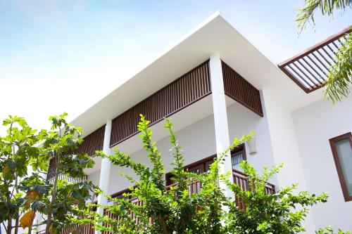an external view of a white building with trees at Villa Aria Boutique Muine in Mui Ne