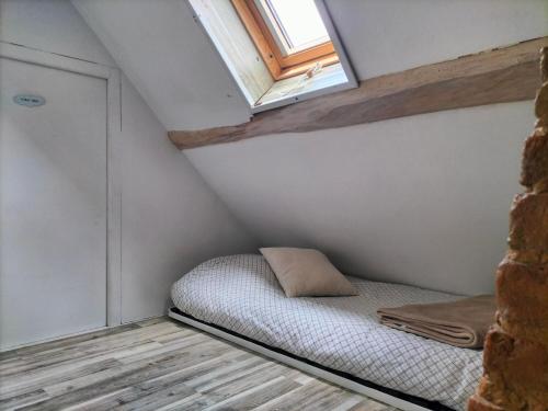 un piccolo letto in una piccola stanza con finestra di Gîte des Cornettes a Écardenville-sur-Eure