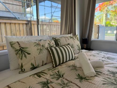 Una cama con almohadas frente a una ventana. en Chic Urban Escape in Norman Park, en Brisbane