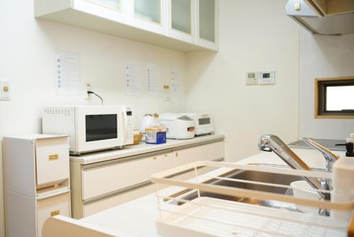 a kitchen with a sink and a microwave at Private stay MIYAJIMA tonbo-AND in Hatsukaichi
