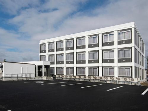 a large white building with a parking lot at ドリームビレッジエンシン in Kitakami