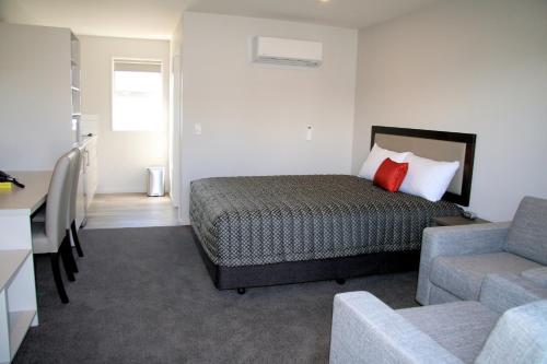 a bedroom with a bed and a couch and a chair at Oxford Village Motels in Oxford