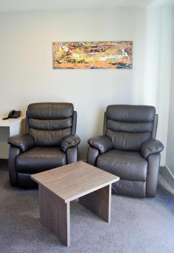 two leather chairs and a coffee table in a room at Oxford Village Motels in Oxford