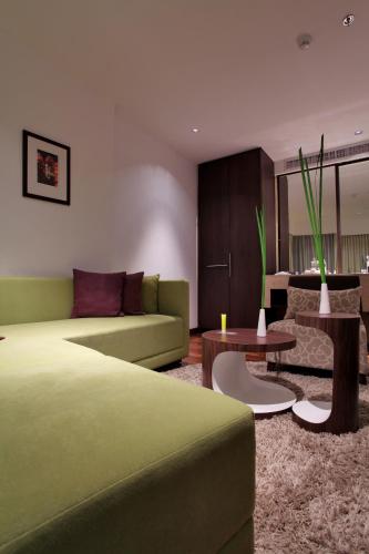 a living room with a green couch and a table at LiT BANGKOK Hotel in Bangkok