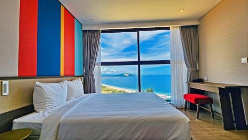a hotel room with a bed and a large window at Mandala Hotel & Resort 5 Star in Mui Ne