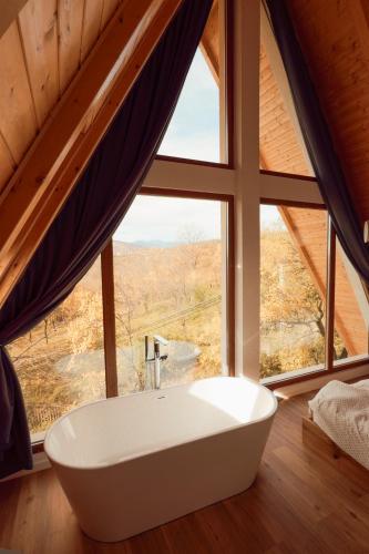 a bathroom with a tub in front of a large window at The Cliff Village in Comarnic