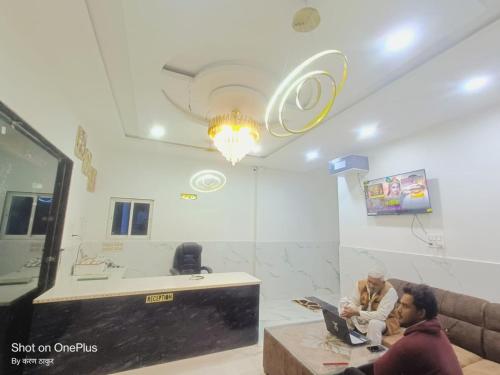 two people sitting in a waiting room with their laptops at Om Baikunth Dham in Vrindāvan