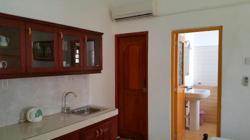 a kitchen with wooden cabinets and a sink and a bathroom at Holiday Fashion Inn in Negombo