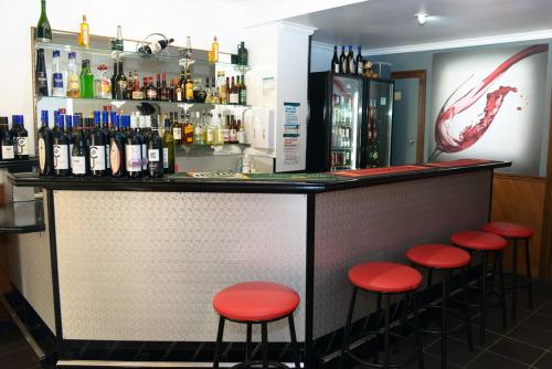 a bar with red stools in front of a counter at Bandicoot Motor Inn Hamilton in Hamilton