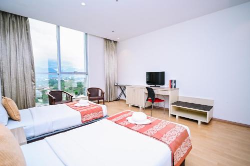 ein Hotelzimmer mit zwei Betten und einem Schreibtisch in der Unterkunft Kingston Hotel 15 - Tower Regency, Ipoh in Ipoh