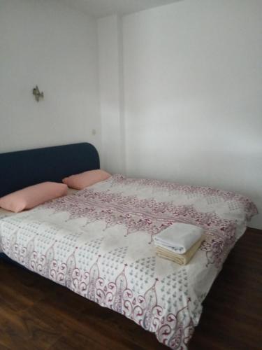 ein Bett mit einer rosa-weißen Bettdecke und zwei Büchern in der Unterkunft carshija in Struga