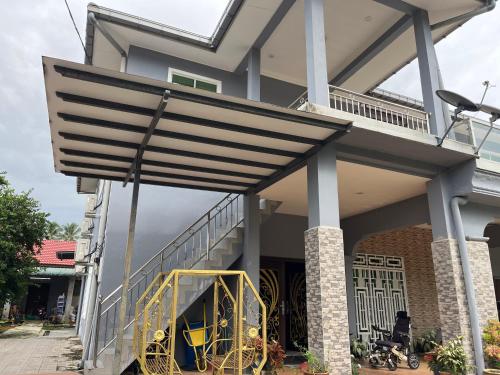 Kuala KeraiHOMESTAY Tok Mek的房子侧面的遮阳篷下摆放着黄色椅子