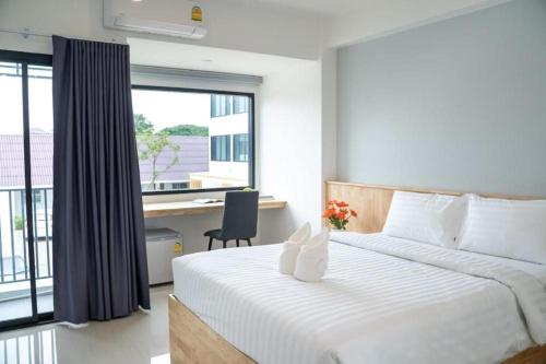 a bedroom with a bed and a desk and a window at Meesuk ChiangRai Hotel in Chiang Rai