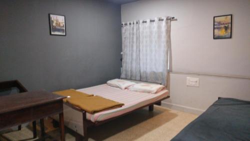 a room with a bed and a table and a window at Cherry On The Top Homestay with AC in one bedroom in Kolhapur