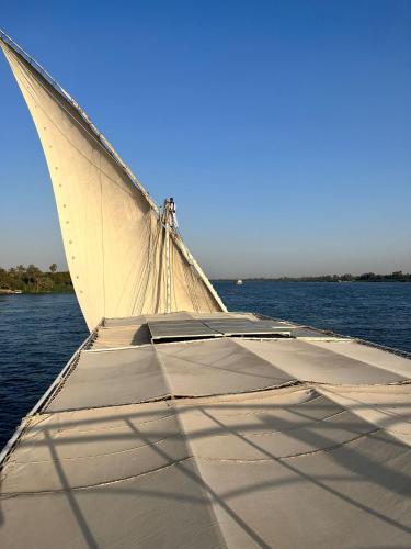 a boat with a white sail on the water at Nile SE Felucca nile cruise private tour in Naj‘ al ‘Amrāb