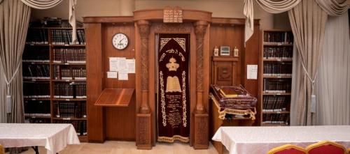 a large clock in a library with shelves of books at Aristocrat Hotel Haredi in Bnei Brak