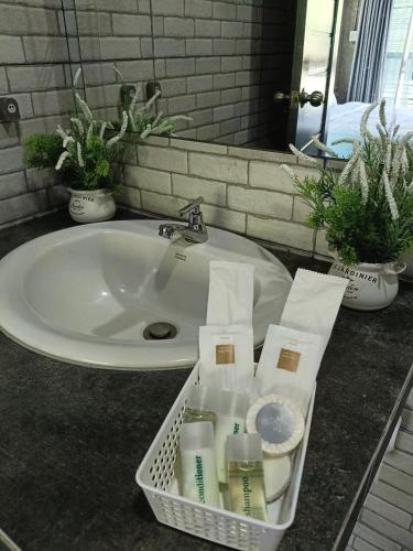 a bathroom sink with a basket of toiletries on a counter at Baan suan khun Pen Chiangmai in Ban Luam