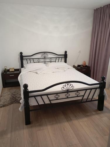 a bedroom with a bed with white sheets and wooden floors at Casa Camelia in Craiova