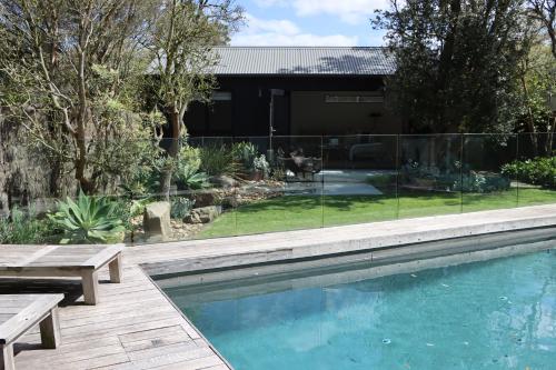 a swimming pool with a table and benches next to a house at Driftwood Studio in Mount Martha