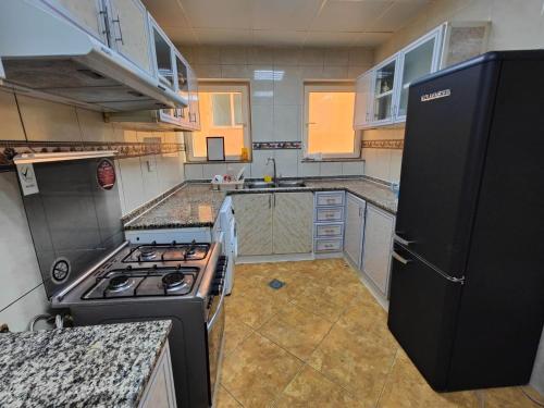 a small kitchen with a stove and a refrigerator at Delightful Private Rooms with Garden View in Sharjah